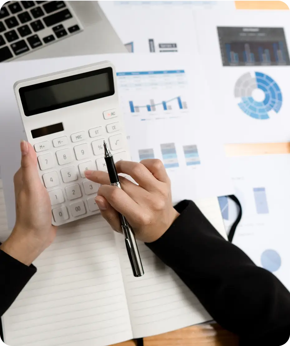 Hands using calculator and pen over financial charts